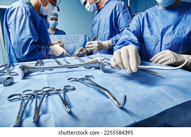 Surgical Team. Surgical nurse giving surgical scissors to male surgeon during operation in operating theatre - Powered by Shutterstock