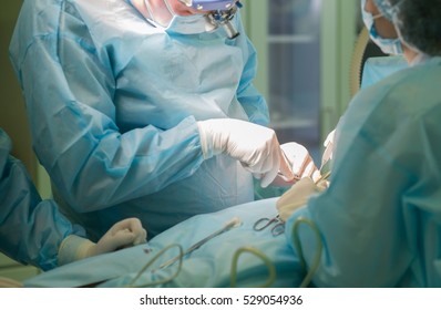 Surgical Team Performing Cosmetic Surgery In Hospital Operating Room. Breast Augmentation At Medical Clinic. Breast Enlargement, Enhancement. Mammaplasty