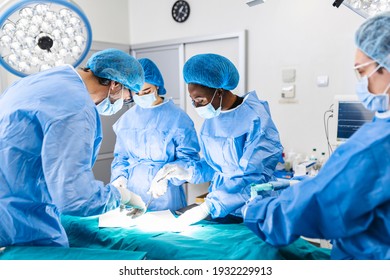 Surgical team performing surgery in modern operation theater,Team of doctors concentrating on a patient during a surgery,Team of doctors working together during a surgery in operating room, - Shutterstock ID 1932229913