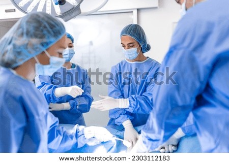 Surgical team performing surgery in modern operation theater,Team of doctors concentrating on a patient during a surgery,Team of doctors working together during a surgery in operating room,