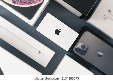Surgut  Russia - March 05, 2022 : The top view of white  iPhone smartphone box with logo: iPhones, headphones, watches are on a grey background. The concept of the packaging of apple products.