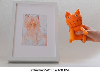 Surgut, Russia - March 27 2021: Handmade Felt Sad Toy Orange Cat In The Hand Of A Child. The Concept Of A Toy Based On A Child's Drawing