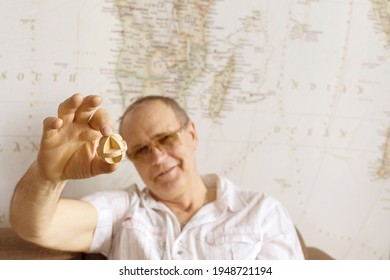 Surgut, Russia - Murch 27, 2021: A Wooden Puzzle In The Hand Of A 65 Year Old Smiling Man. Dementia Therapy With Wooden Puzzle. 