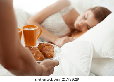 Surprise breakfast for sleeping woman in bed