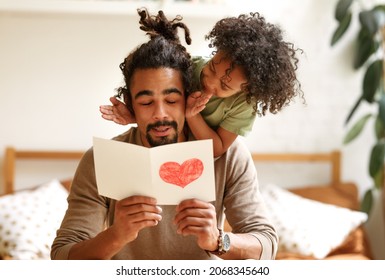 Surprise for daddy. Cute smiling afro american kid son giving father postcard with red drawn heart and covering his eyes with hands, happy child congratulating dad during family holiday at home - Powered by Shutterstock