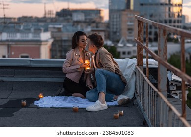 Surprise date on rooftop with urban cityscape and skyscrapers on background. Happy young loving couple drinking wine having romantic candlelit dinner celebrating anniversary or Valentines Day - Powered by Shutterstock