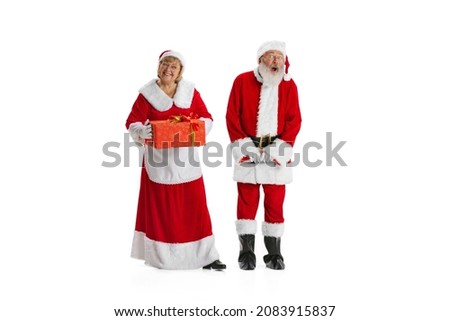 Surprise. Excited old man in Santa Claus costume and smiling woman, missis Claus with gift boxe isolated on white background. Family, care, holidays, wishes, dream concept, Christmas, New Year 2022.