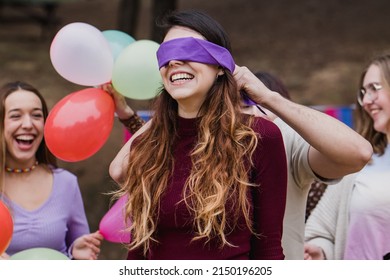 Sorpresa en la fiesta de cumpleaños, grupo de amigos jugando con la venda de los ojos y riendo.