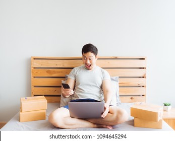 Surprise And Shock Face Of Asian Man Success On Making Big Sale Of His Online Store. Concept Of Freelance Startup And Online Business Home Office.