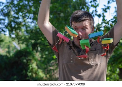 Surprised Adult Man Holds Children's Ships Tied To A Branch. Five Homemade Sailboats Hanging From Strings In Front Of The Persona's Face. Outside The Room. Selective Focus.