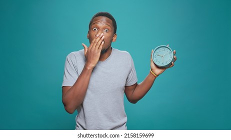 Surprised adult in shock looking at time on watch and rushing, running late to appointment. Male model being shocked about delay and hurry, checking hours and minutes on wall clock. - Shutterstock ID 2158159699