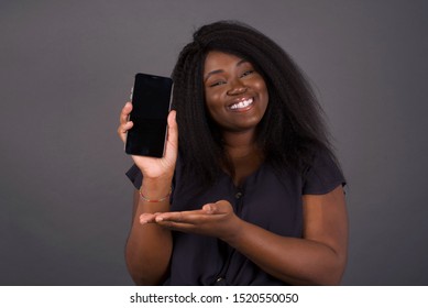 Surprised African American Young Woman Showing And Pointing At Empty Phone Screen With Open Palm.