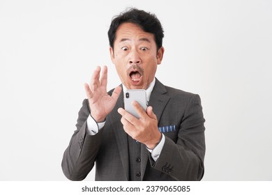 Surprised Asian middle aged businessman with the smartphone in white background - Powered by Shutterstock