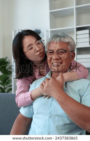 Surprised Asian woman hugs elderly father Teasing in various verses Reading in the living room holidays family relationships Holiday celebration Father's Day and elderly people's health care concept.