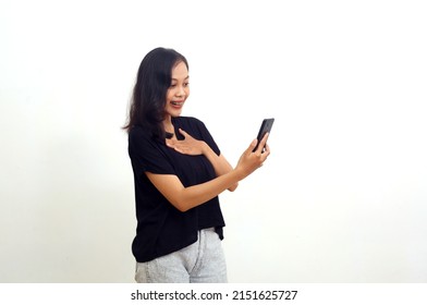 Surprised Asian Young Woman Standing While Looking At Her Cell Phone. Isolated On White