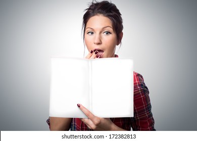 Surprised Attractive Young Woman Holding Magazine With Empty Cover In Her Hand.