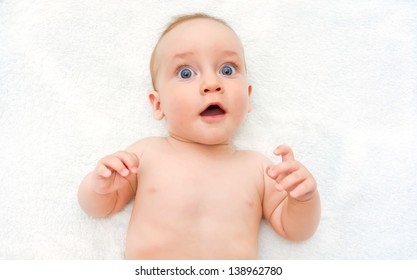 The surprised baby lying on white towel