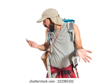 Surprised backpacker talking to mobile over white background
