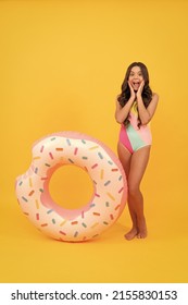 surprised beach child in swimming suit with doughnut inflatable ring, summer activity.