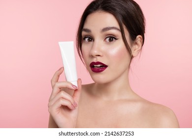 Surprised Beautiful Young Woman Show Mockup Cosmetics Tube With Lotion, Cream Or Makeup Foundation. Modern Girl With Trendy Make Up Holding Cosmetic Package, Advertise Natural Skincare Beauty Product.