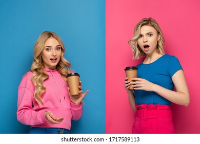 Surprised Blonde Women With Disposable Cups Looking At Camera On Pink And Blue Background