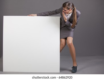 surprised business woman with blank board over grey background