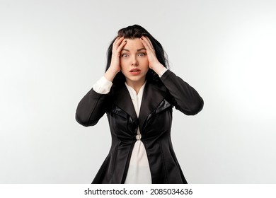 Surprised Businesswoman In Black Formal Jacket White Shirt Over White Background. Shocked Young Woman With Opened Mouth Touching Face. Business Concept