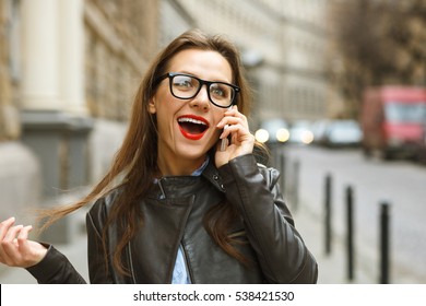 Surprised Businesswoman Walking Down The Street While Talking On Smart Phone