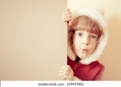 Surprised Child. Funny Kid Holding Christmas Card Blank. Xmas Holiday Concept. Retro Toned Image