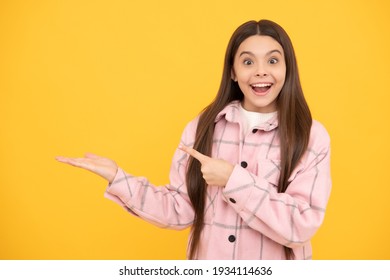 surprised child girl wear pink checkered shirt presenting product, copy space, advertising.