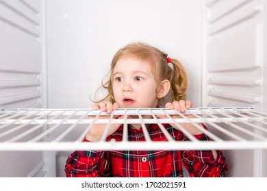 Surprised Child Sitting In An Empty Refrigerator, Close-up