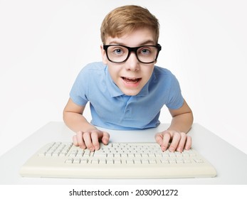 Surprised Child Using Computer Keyboard. Teenage Boy Hacker Typing On Laptop. Funny Kid In Eye Glasses Study Programming Code Over White Studio Background