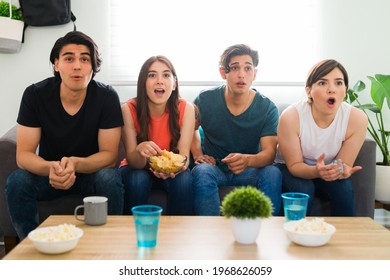 Surprised College Friends Watching A Thriller Movie Or Tv Series On The Sofa And Feeling Shocked While Eating Chips