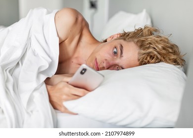 Surprised and concerned man waiting for a phone call while lying on bed and looking at cell phone. Sad teenager read the bad news

 - Powered by Shutterstock