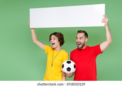 Surprised Couple Friends Sport Family Woman Man Football Fans In T-shirts Cheer Up Support Favorite Team With Soccer Ball Hold Big White Empty Blank Billboard Isolated On Green Background Studio