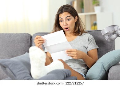 Surprised disabled girl reading notification  sitting on a couch in the living room at home