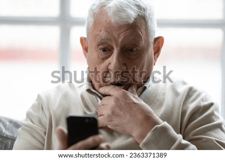 Surprised elderly 80s man using smartphone look at screen shocked by unexpected news or message, stunned mature grandfather amazed by unbelievable text, browsing internet on cellphone gadget