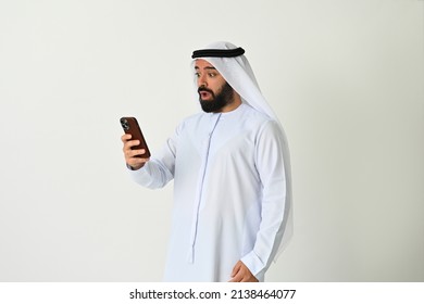 Surprised Emirati Man In UAE Holding Mobile Phone Looking Shocked While Reading An Sms Message On Screen