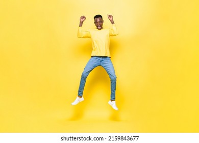 Surprised Excited African Man Jumping With Hands Raised In Studio Yellow Color Isolated Background