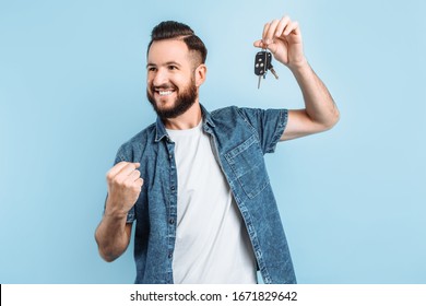 Surprised Excited Happy Man With A Beard Holding Car Keys In His Hands, Standing On An Isolated Blue Background