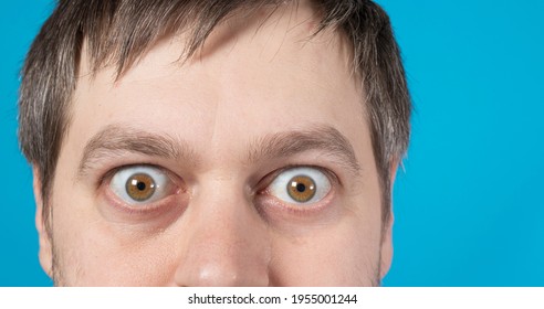 Surprised eyes of a man on a blue background with room for text to copy space. Big bulging eyes. To advertise discounts, sales, pawnshops or credit.