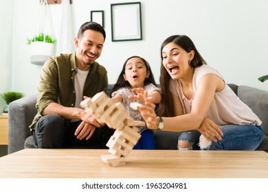 Surprised Family Laughing While Losing A Board Game After A Wooden Stack Falls Down In Their Living Room Table