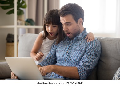 Surprised father and kid girl looking at computer screen using laptop, amazed dad and child daughter excited with unbelievable internet news, shocked by sale offers doing online shopping at home