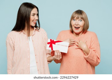 Surprised fun elder parent mom with young adult daughter two women together wears casual clothes hold store gift certificate coupon voucher card isolated on plain blue background. Family day concept - Powered by Shutterstock