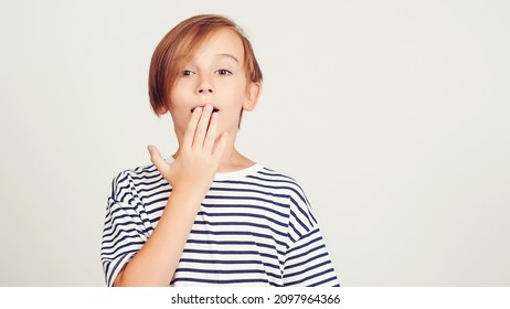 Surprised Fun Impressed Kid Forgetting Something. Face Emotion And Expression. Oops, What Did I Do. Oh No. Boy Thinking About Secret. Face Studio Portrait Of Boy. Shocked Boy Cover Mouth With Hands.