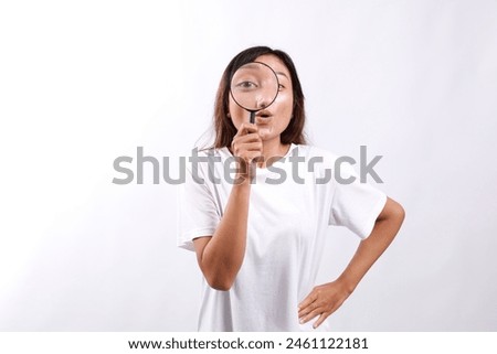 Surprised funny asian woman searching for something, found product, looking through magnifying glass amazed and impressed. Isolated on white