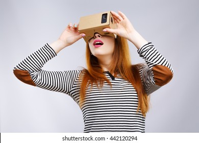 Surprised girl looking at Virtual Reality Glasses. Virtual reality, vr box. Studio, indoors