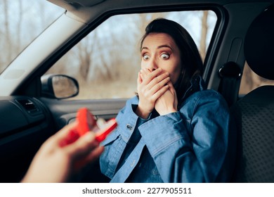 
Surprised Girl Receiving a Marriage Proposal During Car Trip. Funny girlfriend reacting to an unconventional engagement ritual 
