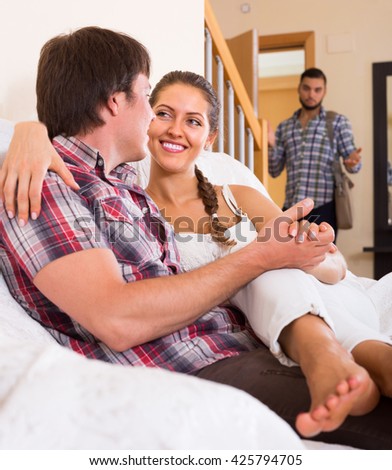 Surprised guy discovering his cheating young attractive wife at home