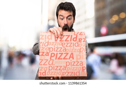 Surprised Handsome man with beard holding pizzas at outdoor